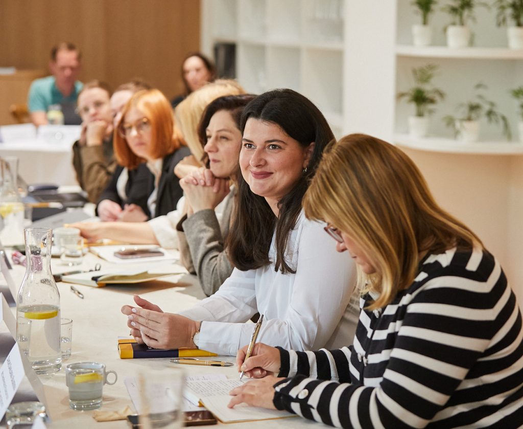 Group session during the NGO leadership workshop in Bratislava. Participants sitting around long tables facing the speaker at the end of the room.