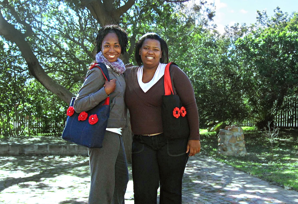 Patrice Gopo (left) and Minah Koela (right), who served as an interpreter in Cape Town for a WDI-funded project, with handbags made by local women business owners in South Africa.