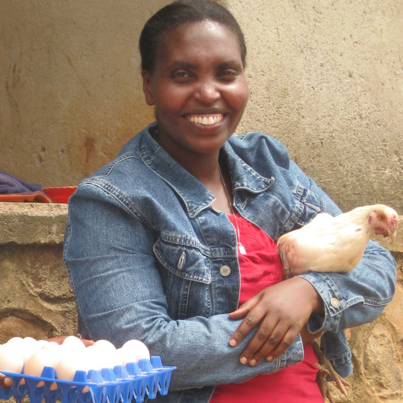 Marie Claire Uwamahoro holds a chicken on her farm