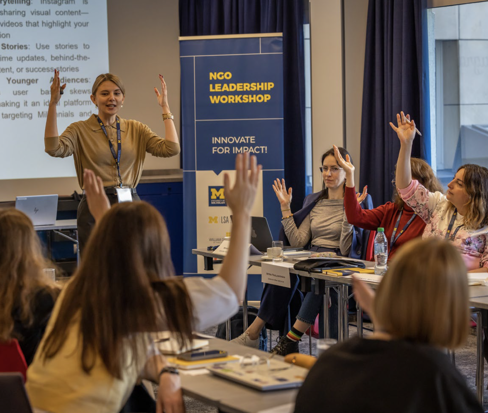 Participants at the NGO Leadership Workshop in Warsaw raising their hands during a session.