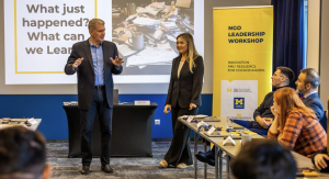 Instructor and participant standing in front of fellow participants during a workshop session.