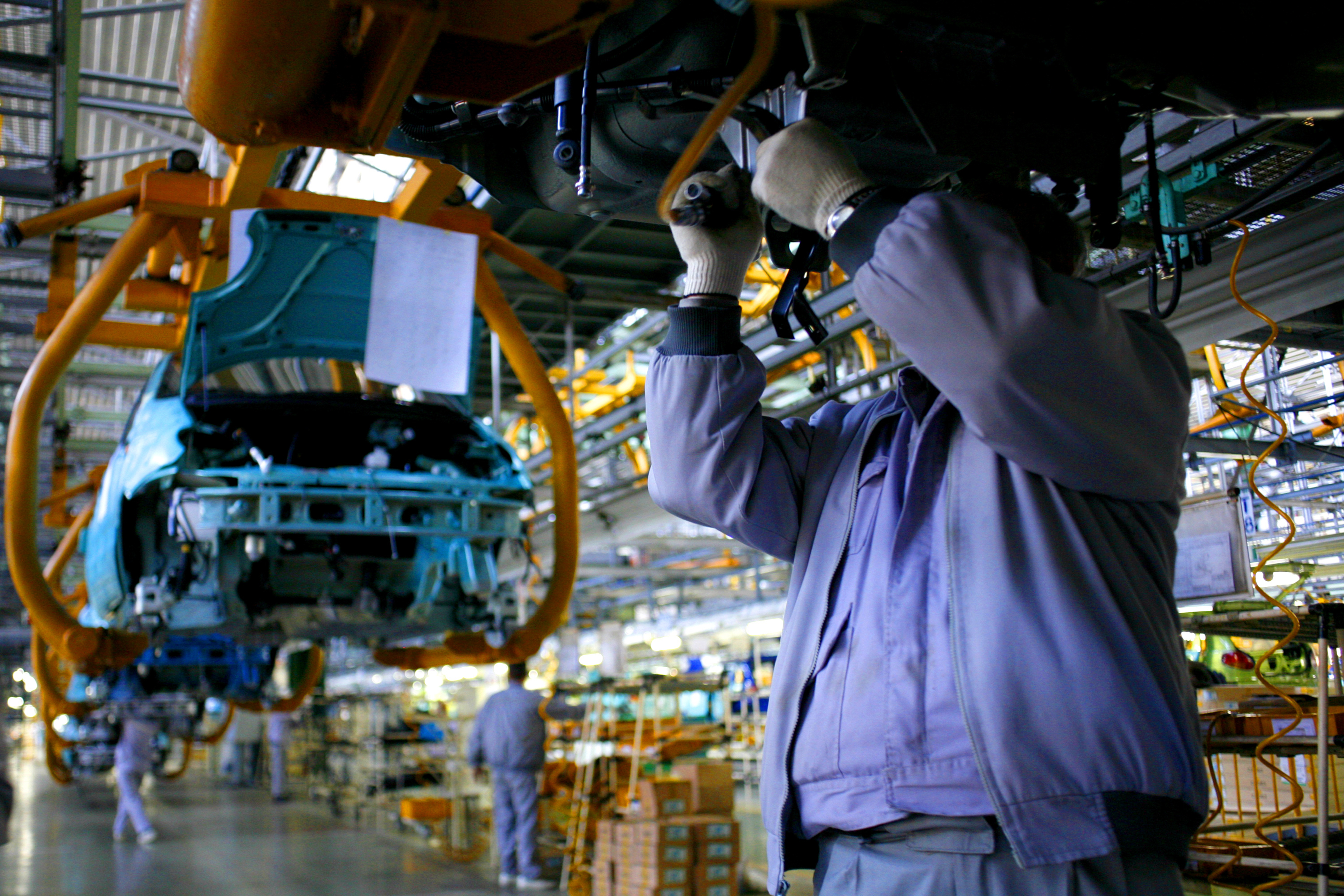 Employee working on a traditional automotive assembly line