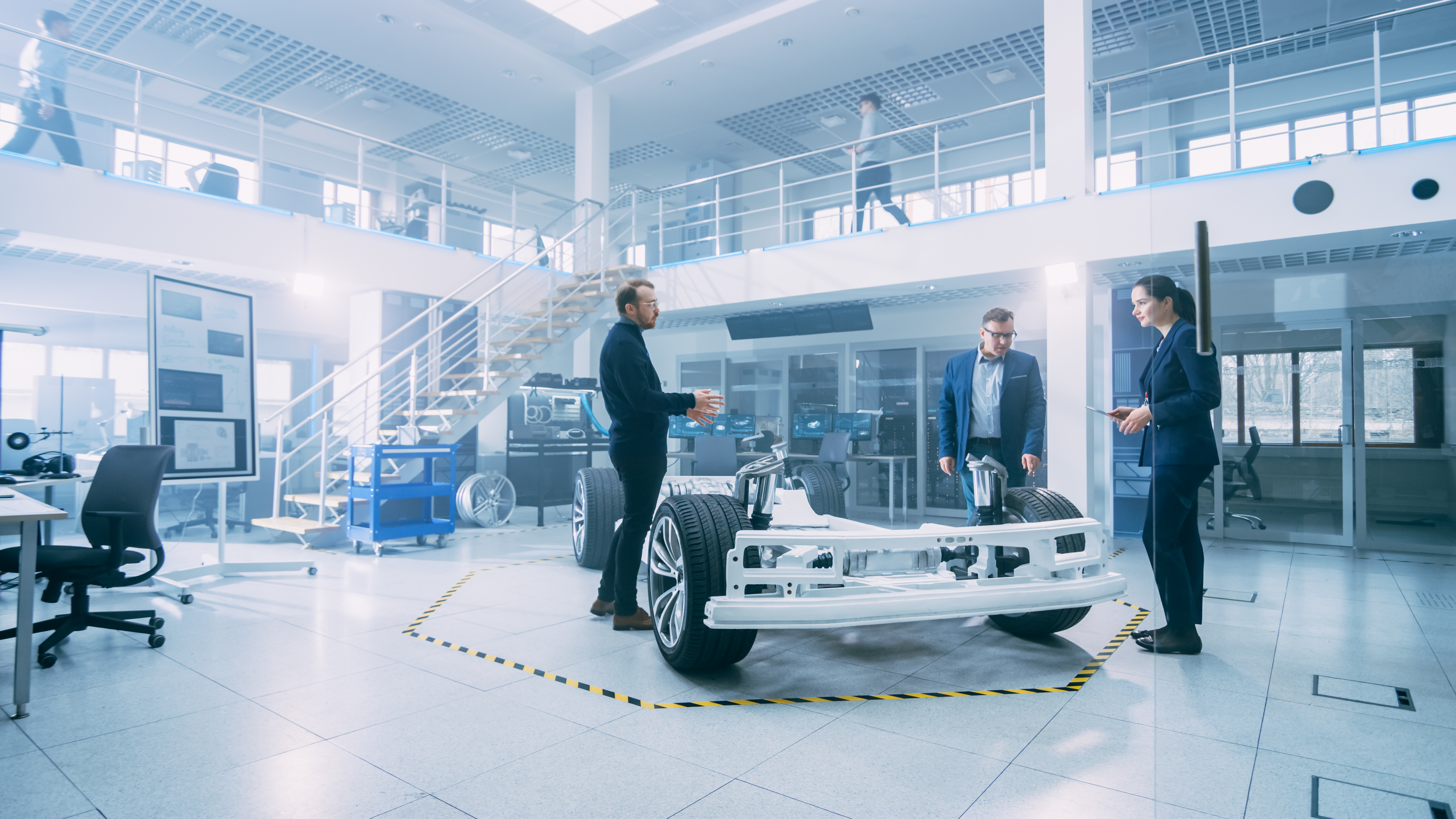 People in a startup lab standing around the chassis of a prototype vehicle