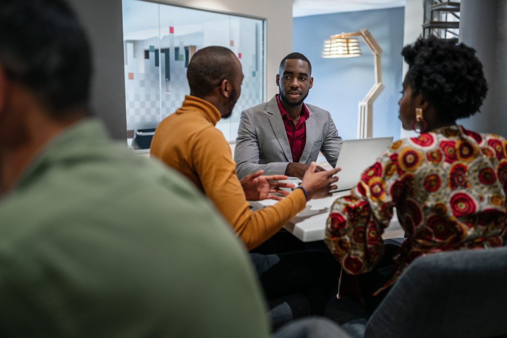 Candid black african business team meeting in discussion sitting in office canteen