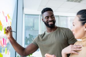 A head of creative team at the company checking how the preparation for the new project is going. She is very satisfied with the creative level the young man has put into the work.