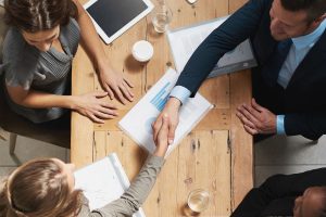 High angle shot of a group of business people shaking hands during a meeting in an office