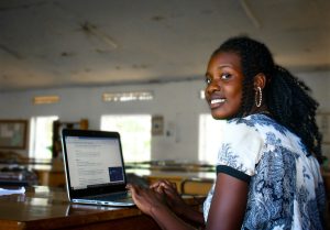 African woman working on a laptop and smiling