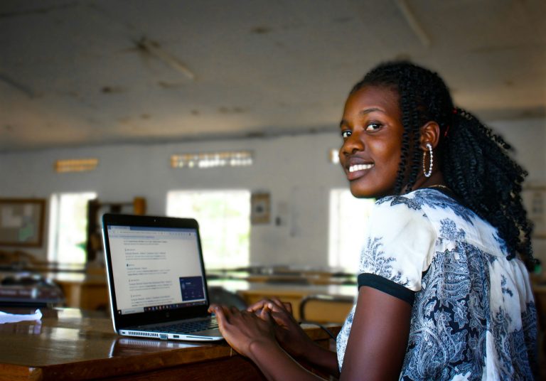 African woman working on a laptop and smiling