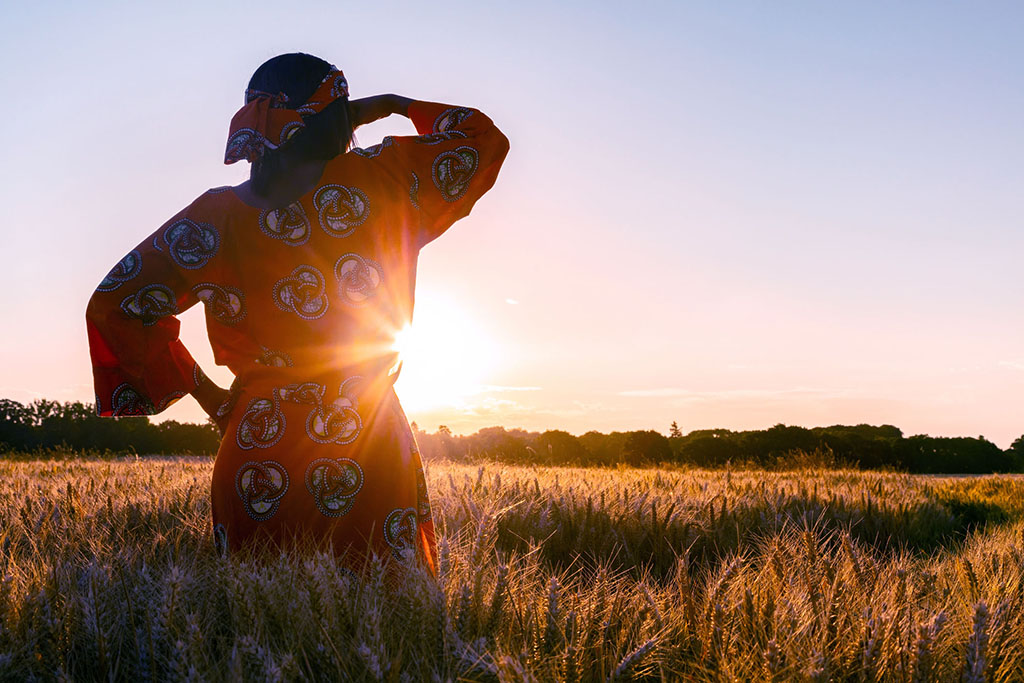 Woman in field in Africa looking towards sunset