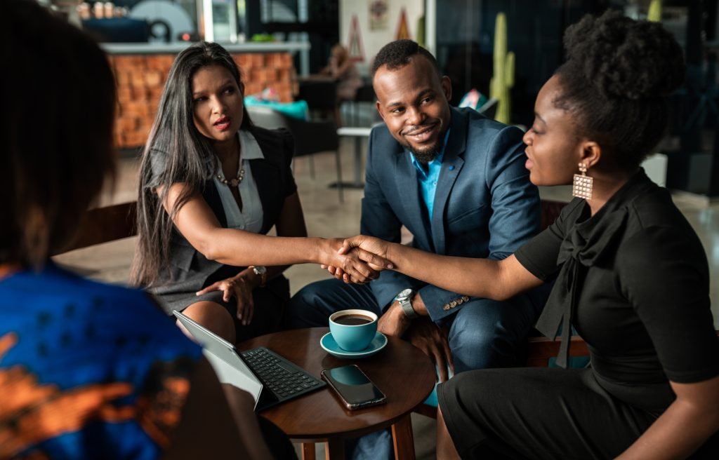 Successful black South African business woman talking and shaking hands with colleagues